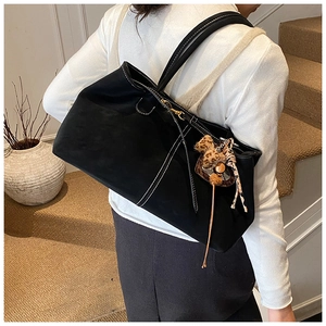 Detail of black tote bag with white stitching and leopard bow tassel accessory