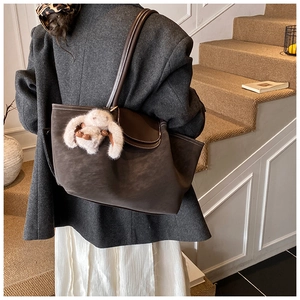 Detail of dark brown matte tote bag with contrast stitching and plush bunny charm