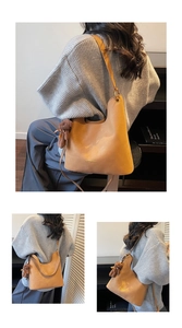 Detail of tan leather tote bag with gold lettering and brown plush bear charm