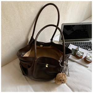 Detail of dark brown tote bag interior with magnetic closure and cute puppy charm accessory