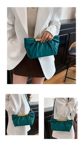 Detail of teal pleated cloud bag featuring a unique gold metal streamlined handle