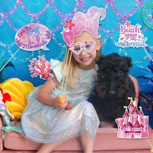 Girl holding mermaid party photo booth props with seashells and shell glasses details