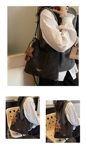 Close-up of black retro leather tote bag with gold logo and brown plush bear charm