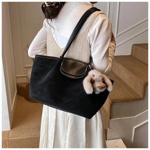 Detail of black tote bag with white contrast stitching and grey plush rabbit charm