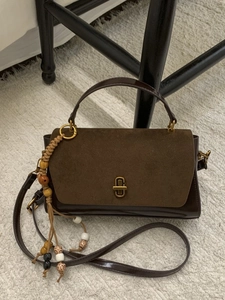 Vintage brown suede patchwork handbag with ethnic tassel on a textured carpet