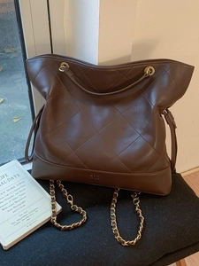 Deep brown quilted leather tote bag with chain strap and gold logo in a retro style