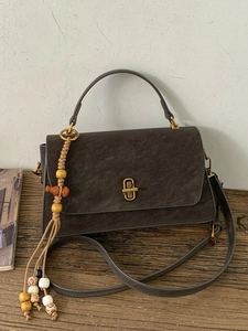 Retro dark coffee matte handbag with gold lock and woven tassel on vintage wood