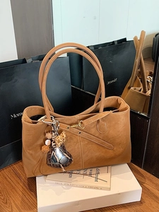 Vintage brown leather tote bag with stylish charms and dual handles for daily commute