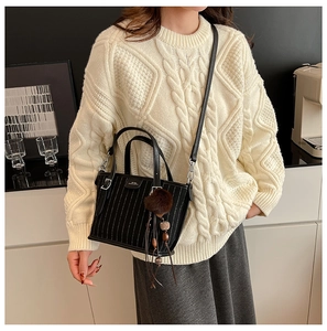 Détail du sac seau noir avec coutures contrastées blanches et pompon en peluche