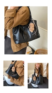 Detail of black large bucket bag with bow tie and cute brown plush bear pendant