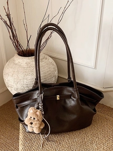Large dark brown leather tote bag with vintage pleated design and plush puppy charm