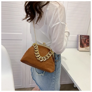 Detail of a brown pleated cloud bag with a chunky gold chain strap shown on a model