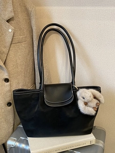 Minimalist black faux leather tote bag with white stitching and plush rabbit pendant