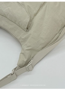 Détail de la texture en nylon plissé et de la bandoulière réglable d'un sac crème