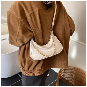 Detailed view of white crescent bag in glossy patent leather with stylish chain strap