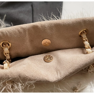 Detail view of suede lining and magnetic gold buckles on a plush feather tote bag