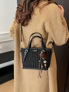 Sac seau vintage à rayures avec charme en peluche porté sur un manteau camel