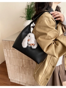 Detail of black lychee grain leather crescent bag with cute white plush rabbit charm