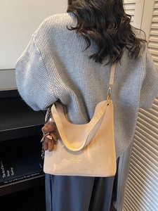 Minimalist oversized khaki tote bag with plush bear charm in a modern home setting