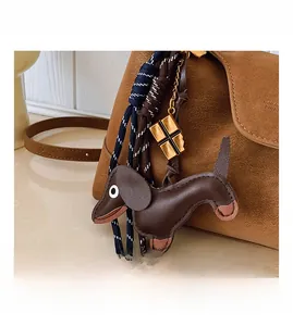 Detailed view of dark brown dachshund leather charm with golden chain on a shoulder bag