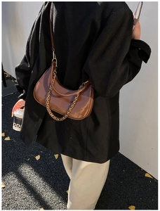 Detail of a brown vintage crescent bag with a gold metal chain and leather strap