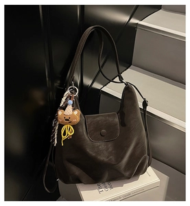 Detail of vintage coffee leather shoulder bag with cute bear charm on Monocle book