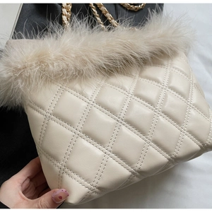 Close-up of cream quilted crossbody bag featuring soft feather trim and gold chain strap