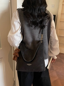 Minimalist black tote bag in suede texture with bear charm worn by a model
