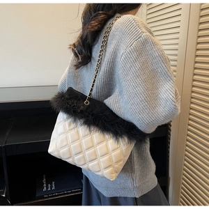 Detail of white quilted handbag with faux fur trim and metal chain strap on model