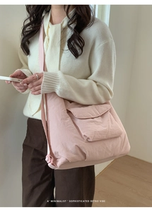 Detail of pink nylon tote bag showing flap pocket and adjustable strap on a model