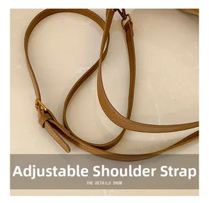 Detail of adjustable caramel leather shoulder strap with gold-tone hardware on pillow bag