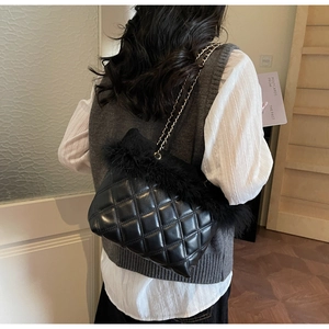 Detail of black quilted shoulder bag featuring plush faux fur trim and elegant chain strap