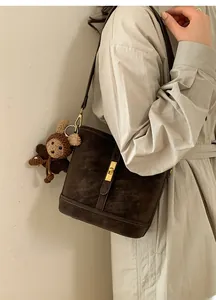 Détail du sac seau en cuir marron foncé avec boucle dorée et pendentif ours au crochet