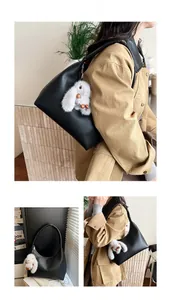 Detail of black pebbled leather hobo bag with a white plush rabbit charm for daily commuting