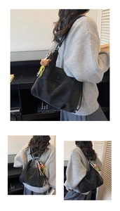 Detail of a black tote bag with plush bear charm showing texture and shoulder strap