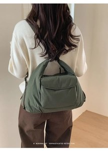 Detail of dark green quilted shoulder bag showing puffy texture and front flap pocket