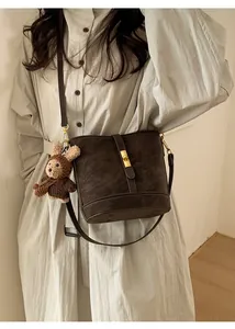 Détail du sac seau rétro marron foncé avec fermoir rotatif en métal et breloque ours en tricot