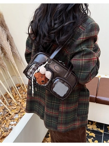 Détail du sac vintage marron foncé avec fenêtre transparente et breloque ours en peluche