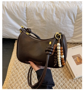 Detail of dark brown leather crescent bag with bohemian beaded tassel and gold zipper