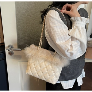 Detail of the diamond-quilted beige shoulder bag with plush faux fur trim and chain strap