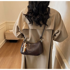 Detail of dark brown leather hobo bag with wooden bead decoration and shoulder strap