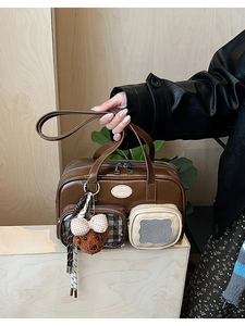 Détail du sac Boston marron avec breloque ours en peluche et poches extérieures utiles