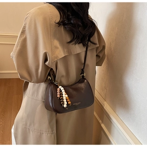 Close-up of a retro brown leather half-moon bag with colorful wooden beaded tassel