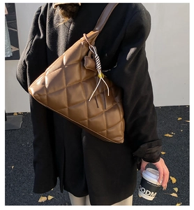 Deep coffee quilted tote bag with classic rhomboid stitching on a model's shoulder
