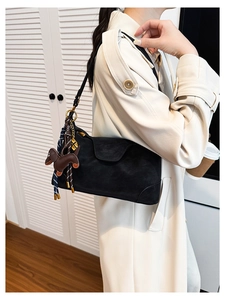 Close-up of black matte shoulder bag featuring a cute brown dachshund leather charm