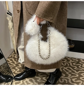 Gros plan du sac en peluche blanc avec chaîne à boules porté sur un manteau en laine