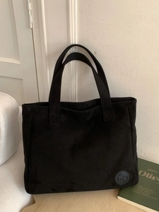 Grand sac cabas minimaliste en daim noir avec doubles poignées dans un décor épuré
