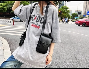 Chic black PU leather crossbody phone bag shown in a real-life urban street setting