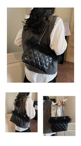 Detail of black quilted chain bag featuring elegant feather trim and gold-tone hardware