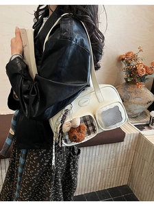 Détail du sac à bandoulière blanc crème avec poches décoratives et pendentif ourson
